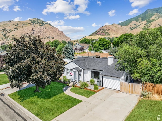 view of front of house featuring a mountain view, concrete driveway, roof with shingles, a chimney, and a garage