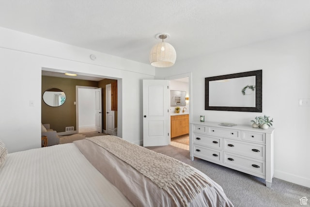 bedroom with light colored carpet, baseboards, and ensuite bath