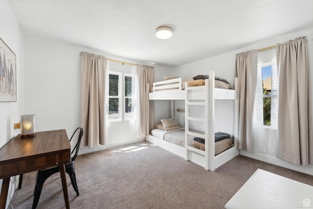 carpeted bedroom featuring multiple windows and an office area