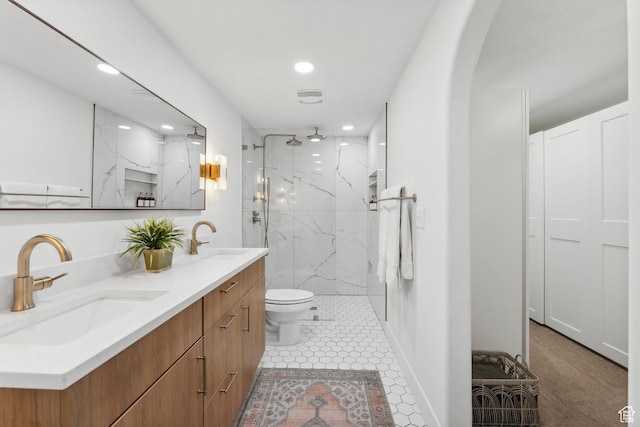 bathroom with recessed lighting, a marble finish shower, double vanity, and toilet
