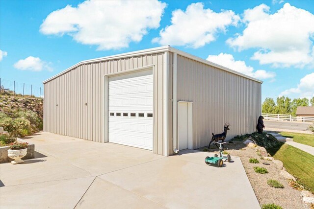 detached garage featuring fence and concrete driveway