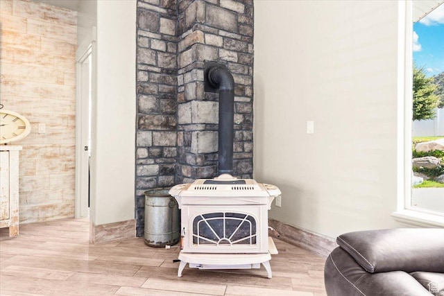 detailed view of a wood stove, wood finished floors, and baseboards