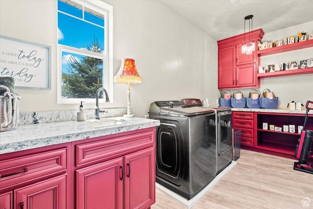 washroom featuring washer and dryer, light wood finished floors, and cabinet space