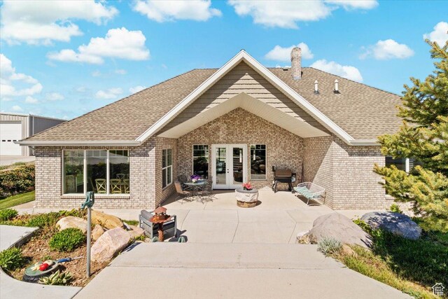 rear view of house with french doors, brick siding, a chimney, and a patio area