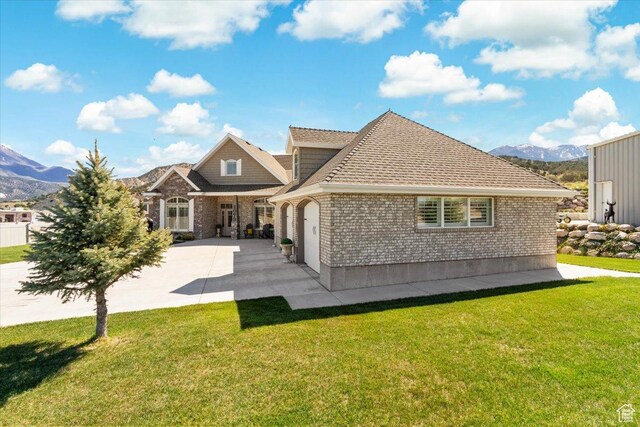 rear view of property with a mountain view, brick siding, and a lawn