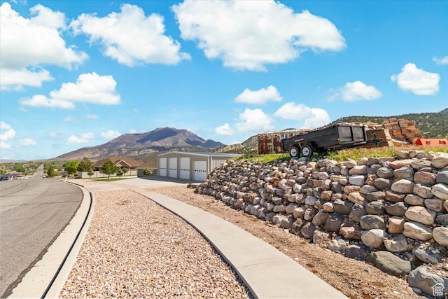 view of property's community with a mountain view, concrete driveway, an attached garage, and an outdoor structure