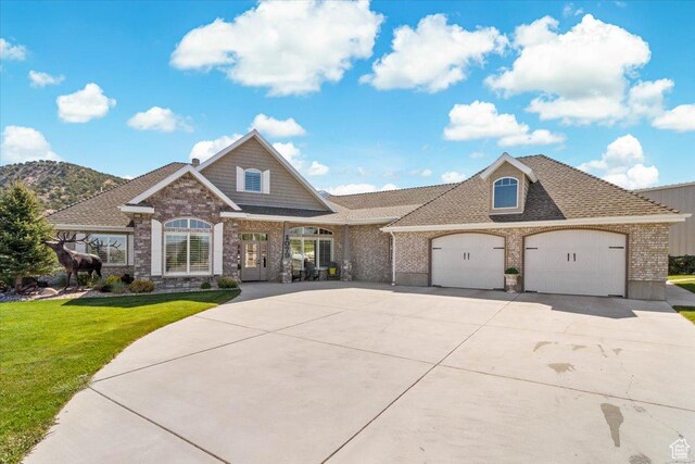 view of front facade with driveway, a garage, a front yard, brick siding, and a shingled roof