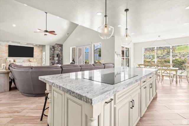 kitchen with black electric stovetop, light wood-style flooring, a ceiling fan, recessed lighting, and a center island