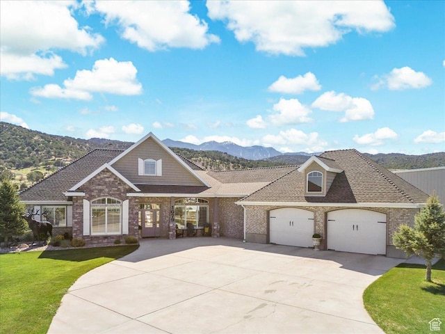 view of front of home featuring a mountain view, a front lawn, concrete driveway, brick siding, and a garage