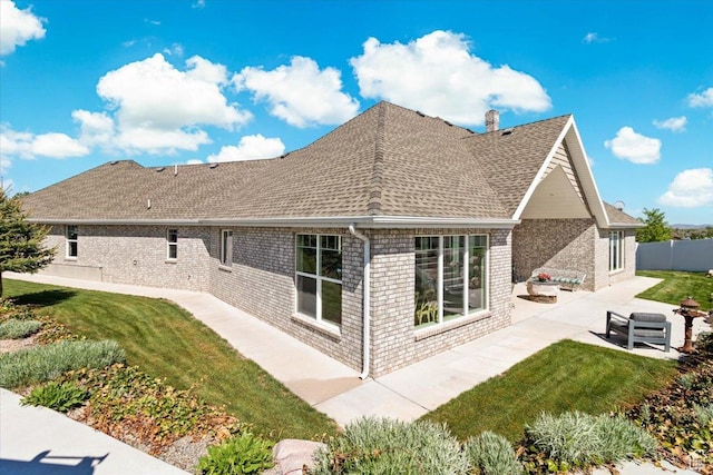 rear view of house featuring a patio area, brick siding, a shingled roof, and a chimney