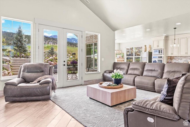living room featuring light wood-style floors, french doors, healthy amount of natural light, recessed lighting, and high vaulted ceiling