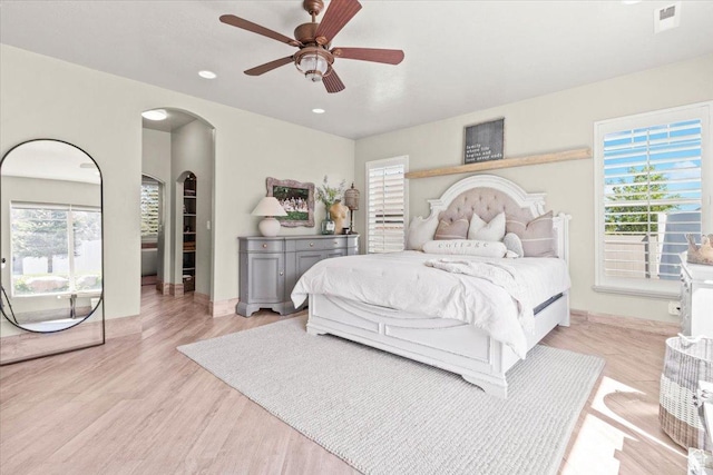 bedroom with light wood finished floors, arched walkways, recessed lighting, baseboards, and a ceiling fan
