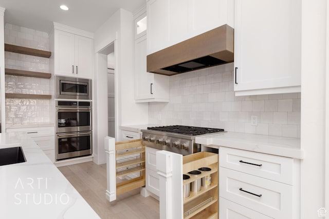 657 E Royal Dr, Washington, UT 84780 - kitchen featuring open shelves, wall chimney exhaust hood, stainless steel appliances, light stone counters, and white cabinetry