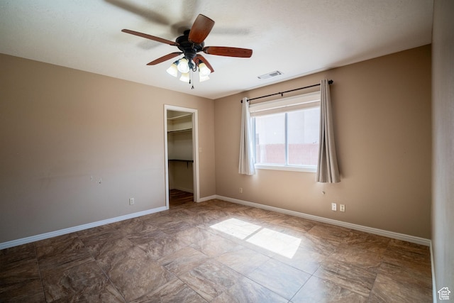 unfurnished bedroom with baseboards, a walk in closet, a closet, and ceiling fan