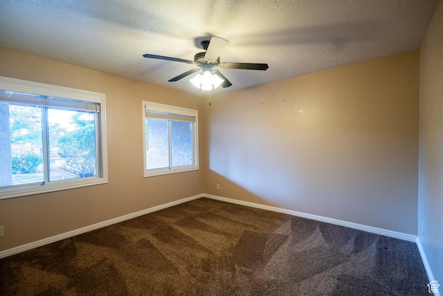 unfurnished room with dark carpet, healthy amount of natural light, baseboards, and a textured ceiling