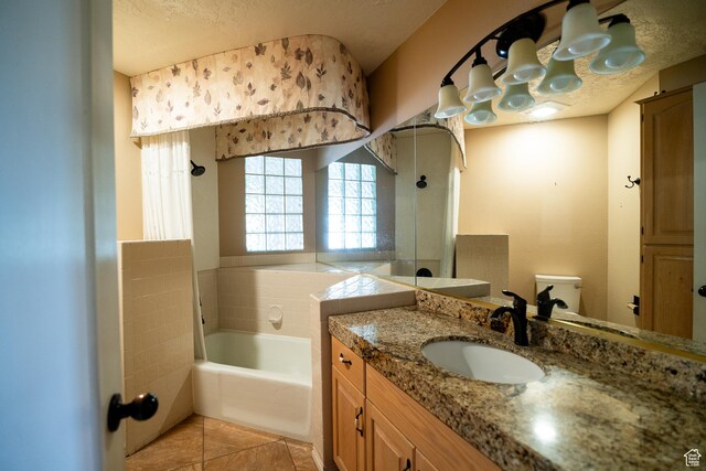bathroom featuring a garden tub, tile patterned flooring, toilet, vanity, and a textured ceiling