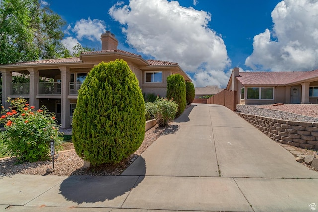 view of home's exterior with a chimney, a tile roof, stucco siding, and fence