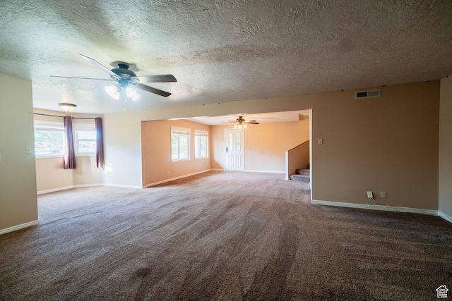 carpeted spare room featuring ceiling fan, baseboards, a textured ceiling, and stairway