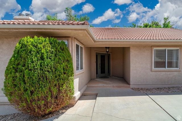view of exterior entry featuring stucco siding and a tiled roof
