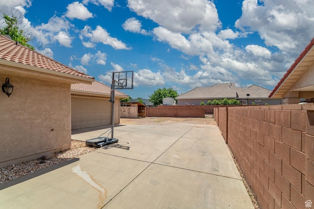view of patio / terrace featuring fence, an outbuilding, and concrete driveway