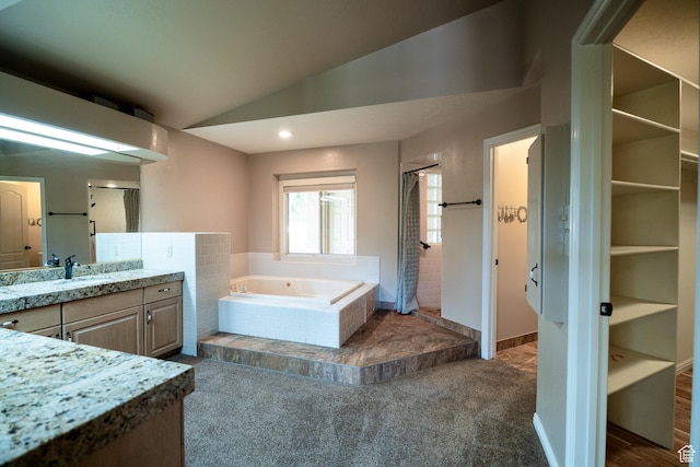 bathroom featuring a shower stall, lofted ceiling, a garden tub, and vanity
