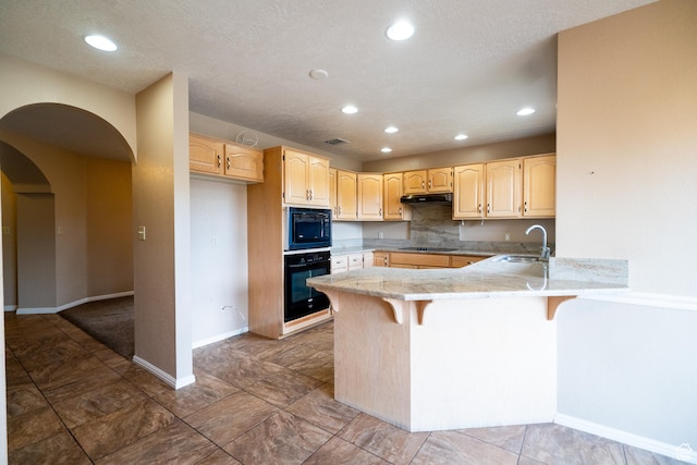kitchen featuring black appliances, a peninsula, under cabinet range hood, light brown cabinetry, and a sink