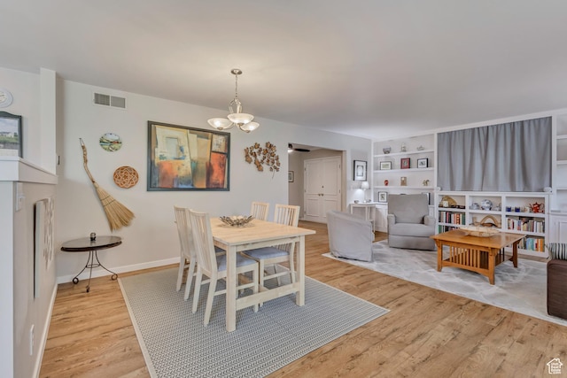 dining space with light wood-style flooring, a chandelier, and baseboards