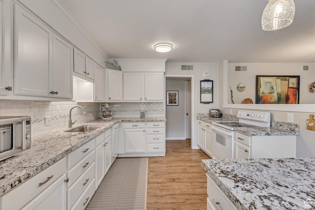 kitchen with white electric range oven, a sink, light wood-type flooring, white cabinetry, and tasteful backsplash