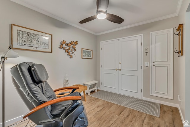 entryway with light wood-style flooring, a ceiling fan, ornamental molding, and baseboards