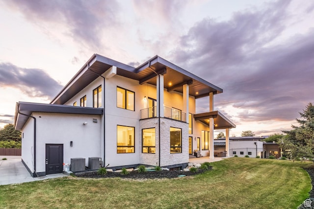 9969 S Altamont Dr E, Sandy, UT 84092 - back of property at dusk featuring a balcony, central AC unit, stucco siding, and a patio