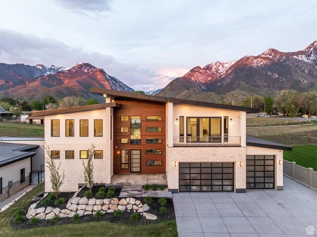 9969 S Altamont Dr E, Sandy, UT 84092 - contemporary home with a mountain view, concrete driveway, an attached garage, fence, and stucco siding