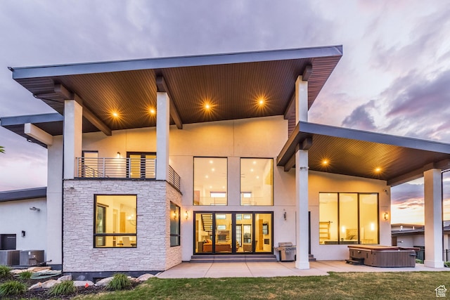 9969 S Altamont Dr E, Sandy, UT 84092 - back of house featuring a hot tub, stone siding, stucco siding, and central AC
