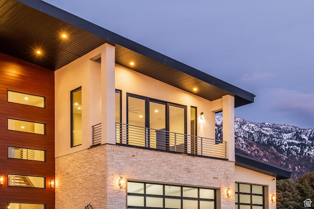 9969 S Altamont Dr E, Sandy, UT 84092 - view of side of home with stone siding, a balcony, stucco siding, and a garage