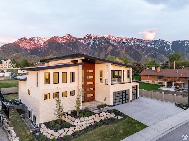9969 S Altamont Dr E, Sandy, UT 84092 - modern home featuring driveway, a mountain view, a balcony, fence, and an attached garage
