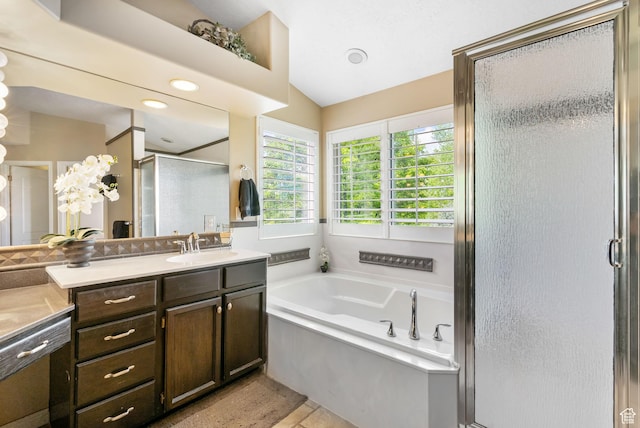 bathroom with a shower stall, vanity, a bath, and vaulted ceiling