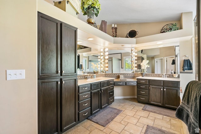 full bathroom with stone tile floors, two vanities, and a chandelier