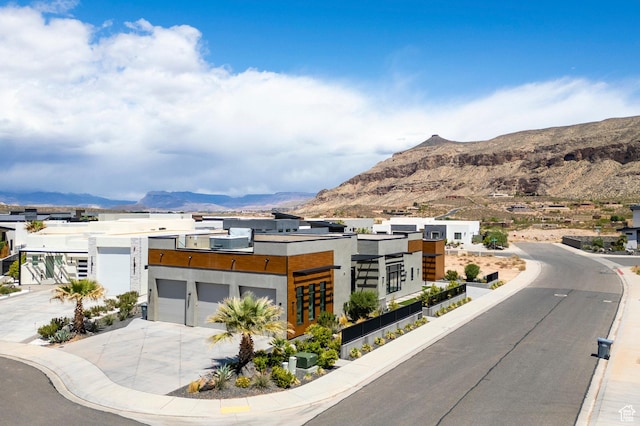 view of asphalt road with a mountain view, curbs, and sidewalks