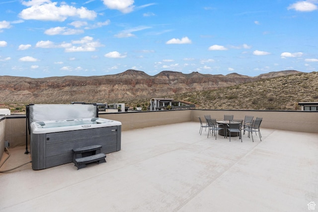 view of patio featuring a hot tub, a mountain view, and outdoor dining space