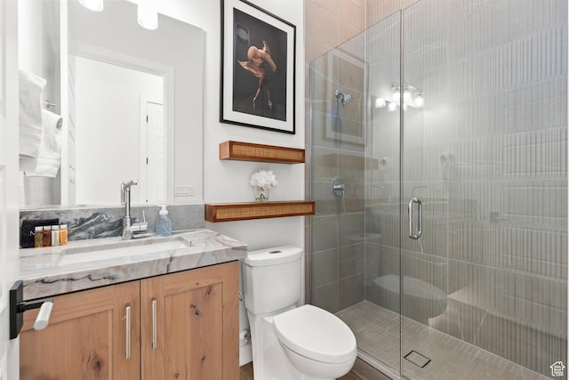 bathroom featuring toilet, a stall shower, and vanity