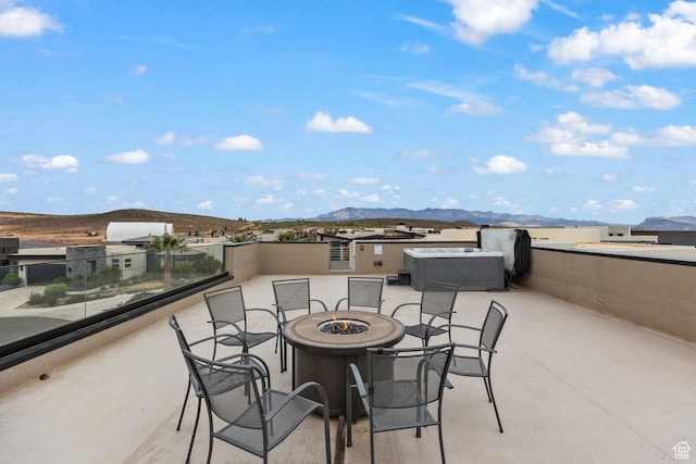 view of patio / terrace featuring an outdoor fire pit, a mountain view, and a covered hot tub