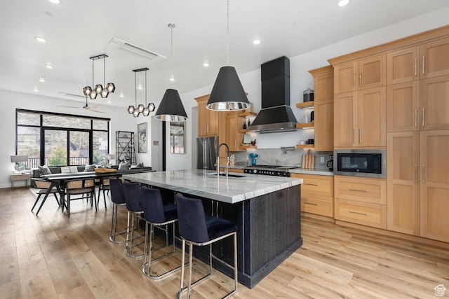 1450 W Torrey Pines Rd, Hurricane, UT 84737 - kitchen featuring built in microwave, wall chimney range hood, an island with sink, light wood finished floors, and recessed lighting