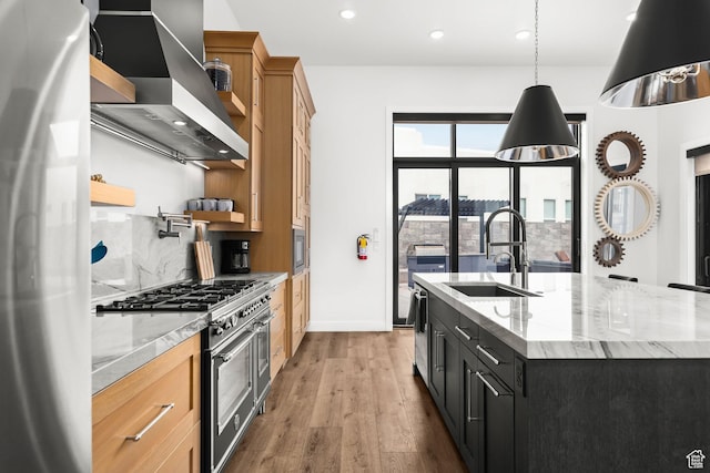 kitchen with stainless steel appliances, a sink, wall chimney exhaust hood, recessed lighting, and wood finished floors