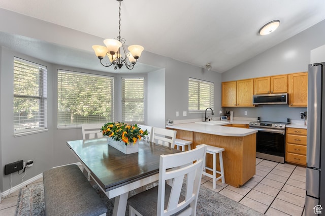 kitchen featuring stainless steel appliances, a sink, vaulted ceiling, light countertops, and a peninsula