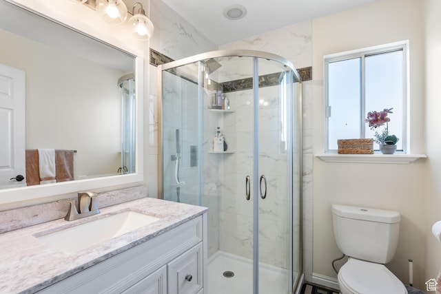bathroom with a stall shower, vanity, and toilet