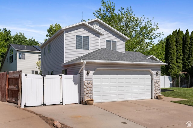 traditional-style house with concrete driveway, a gate, fence, an attached garage, and roof with shingles