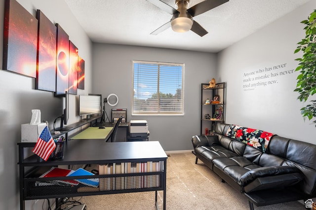 carpeted office space with ceiling fan, baseboards, and a textured ceiling