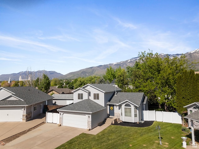 view of front of house featuring concrete driveway, stone siding, a mountain view, and an attached garage