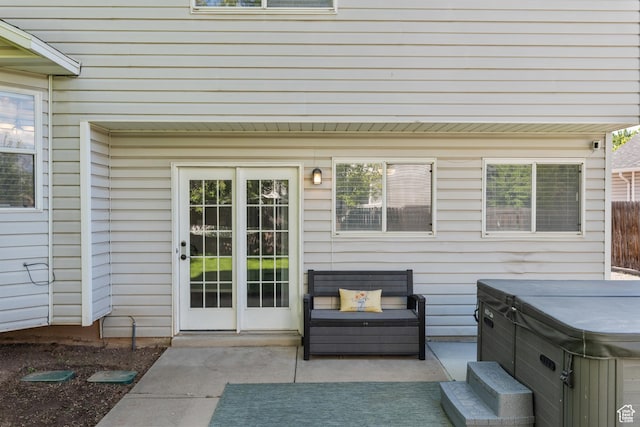 view of exterior entry featuring a hot tub and a patio area