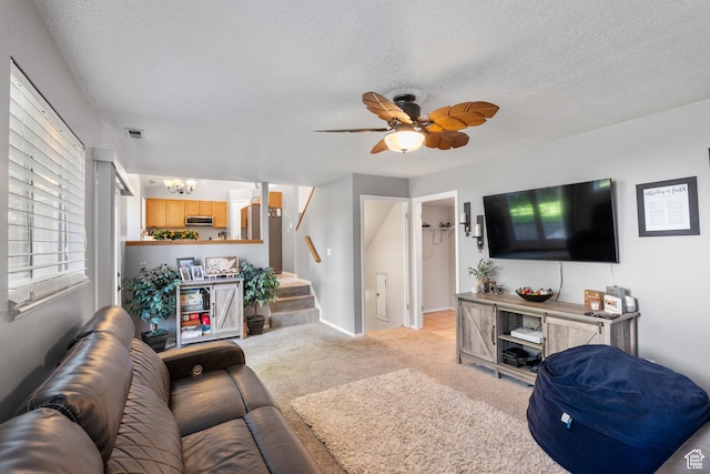 living area with a chandelier, stairs, light colored carpet, a textured ceiling, and ceiling fan