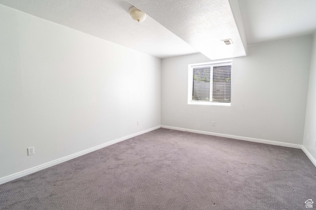 carpeted empty room with baseboards and a textured ceiling